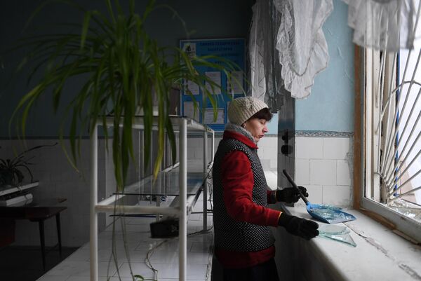 Женщина убирает осколки стекла после обстрела со стороны украинских войск Иловайска