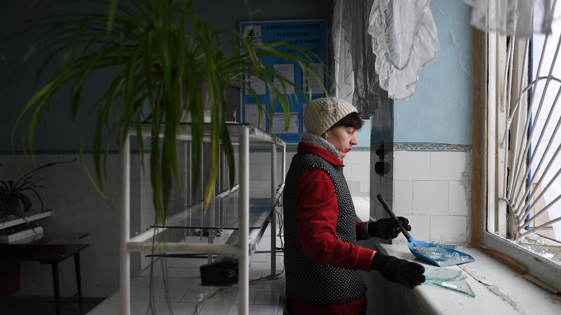 Женщина убирает осколки стекла после обстрела со стороны украинских войск - РИА Новости, 1920, 25.01.2023
