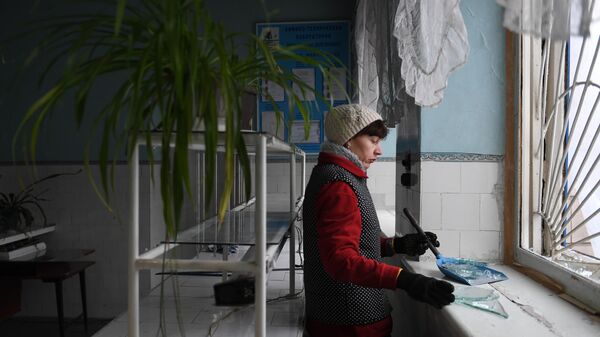 Женщина убирает осколки стекла после обстрела со стороны украинских войск