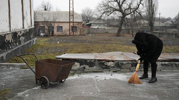 Женщина убирает осколки после обстрела со стороны украинских войск