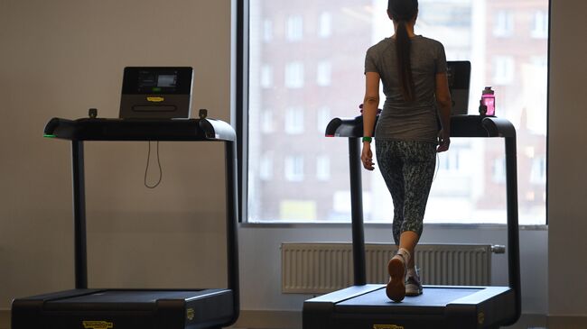 Девушка на беговой дорожке в тренажерном зале