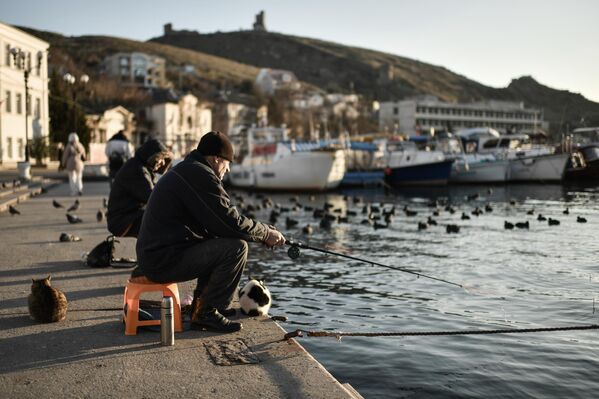 Мужчины рыбачат на набережной Балаклавы