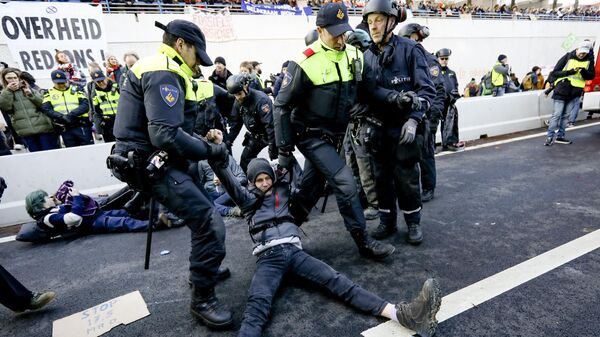 Сотрудники полиции Нидерландов задерживают участника акции протеста в Гааге