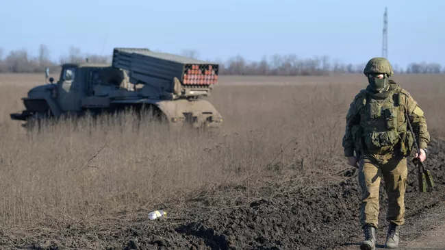 Военнослужащий идет по дороге рядом с реактивной системой залпового огня Торнадо Вооруженных сил России  в южном секторе СВО