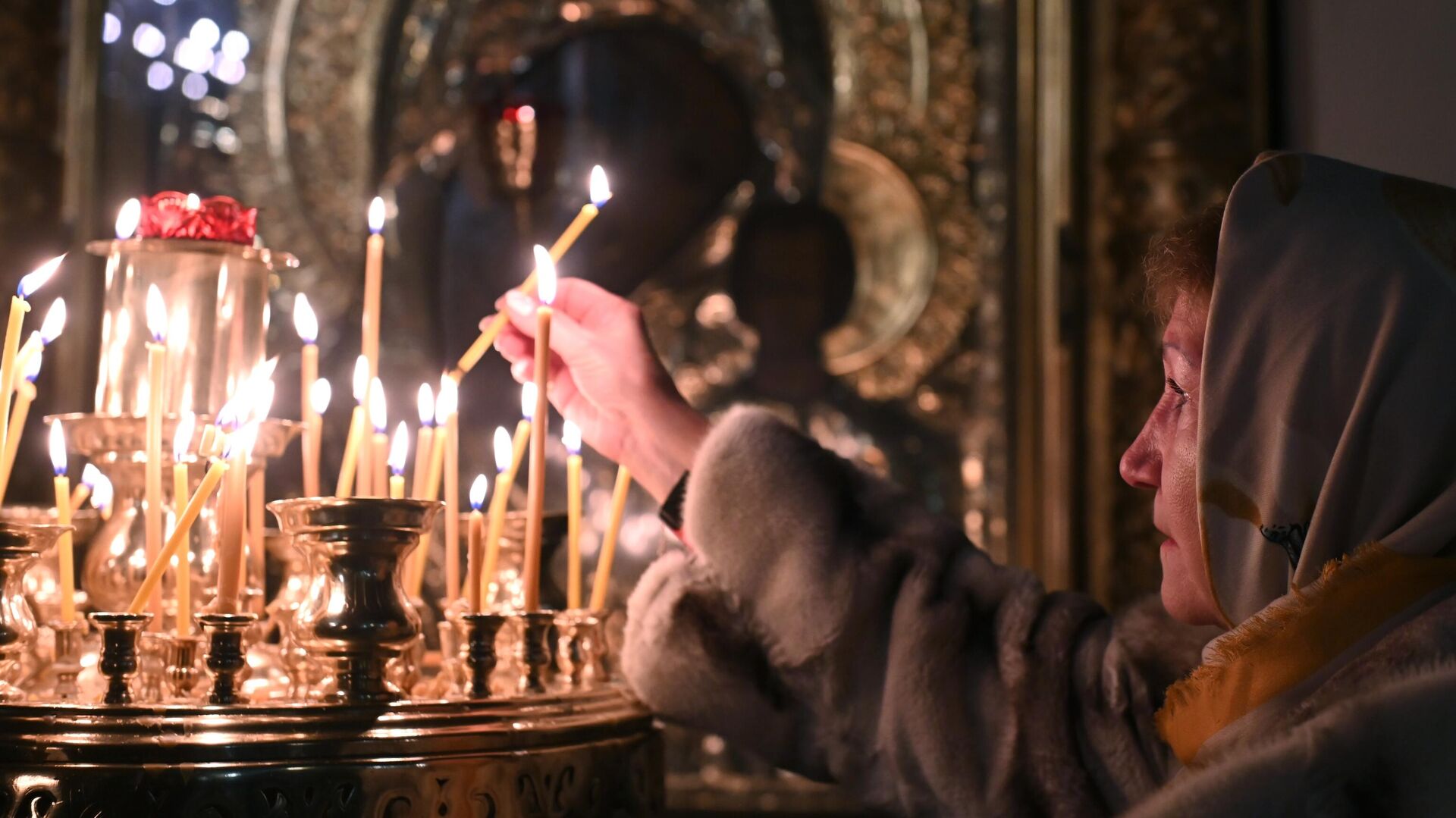 Верующая ставит свечу во время службы - РИА Новости, 1920, 12.02.2024