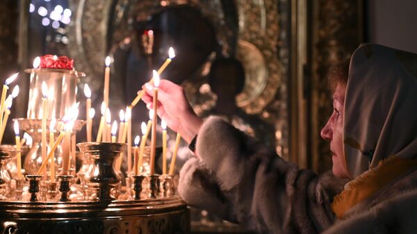 Верующая ставит свечу во время службы