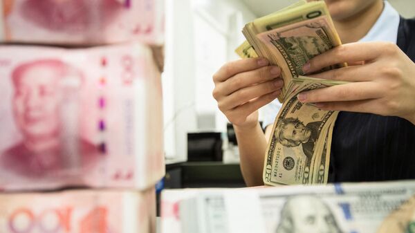 Сотрудник китайского банка пересчитывает банкноты номиналом 100 юаней и доллары США 