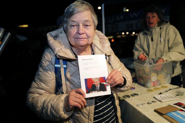Женщина держит в руках портрет президента РФ Владимира Путина на акции протеста против поставок оружия Украине, на одной из улиц в Мюнхене