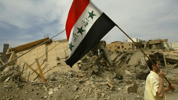 Мужчина с иракским флагом проходит мимо разрушенных бомбардировками США домов в Багдаде