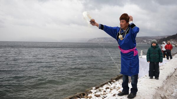 Шаман выплескивает чай в озеро Байкал в ходе обряда на улучшение погоды