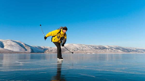 Мужчина катается на коньках на льду озера Байкал