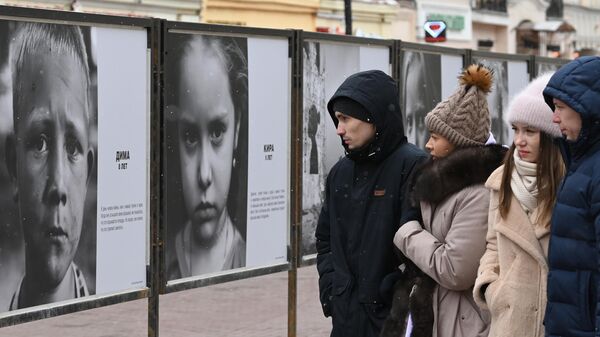 Фотовыставка Посмотри в глаза Донбассу на улице Арбат в Москве, на которой представлены фотографии детей из зоны боевых действий в Донбассе