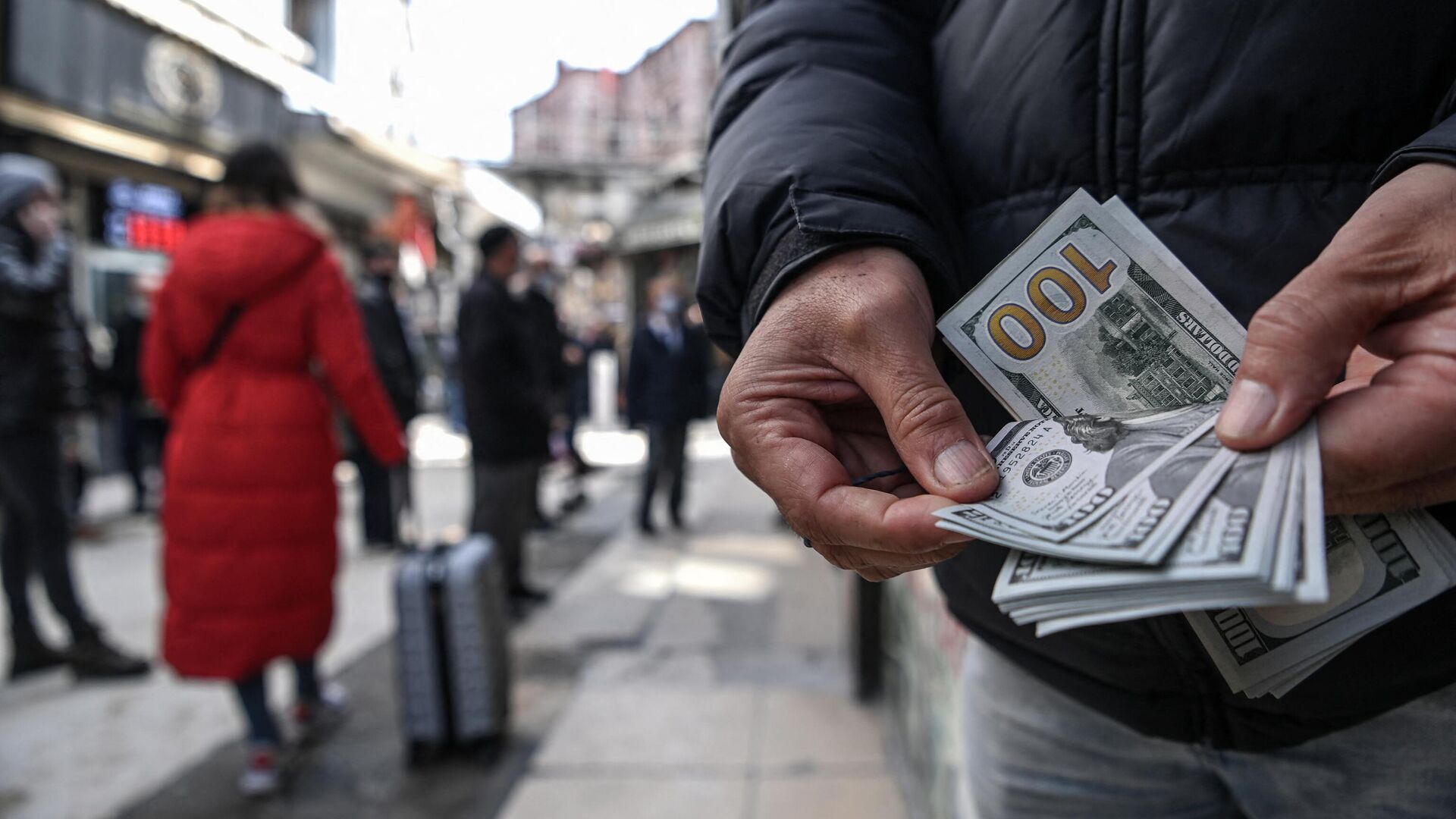 Мужчина пересчитывает доллары США, стоя на улице Стамбула - РИА Новости, 1920, 04.02.2023