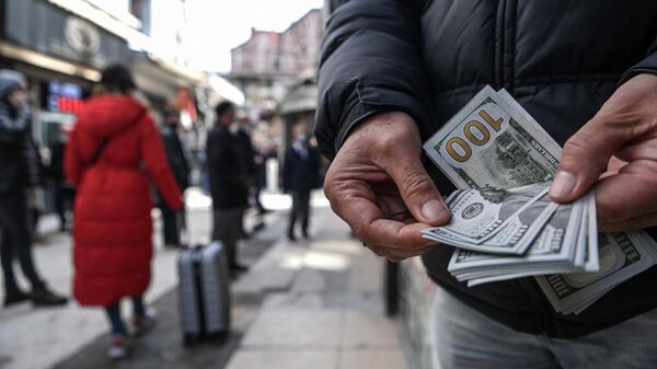 Мужчина пересчитывает доллары США, стоя на улице Стамбула