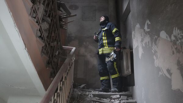 Сотрудник МЧС ДНР на лестничной площадке жилого дома, получившего повреждения в результате обстрела ВСУ