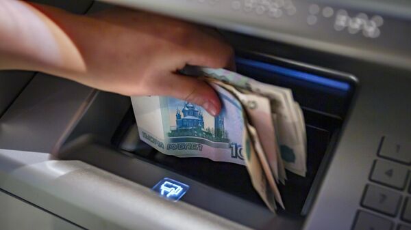 Посетитель берет деньги в банкомате