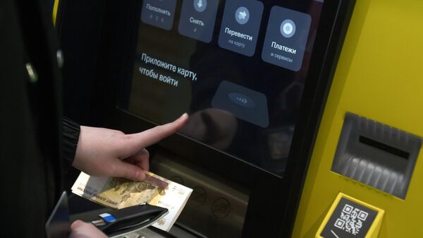 Посетитель кладет деньги на банковский счет в банкомате