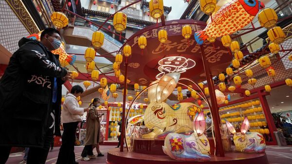 Покупатели в торговом центре Пекина, украшенном к празднику фонарей