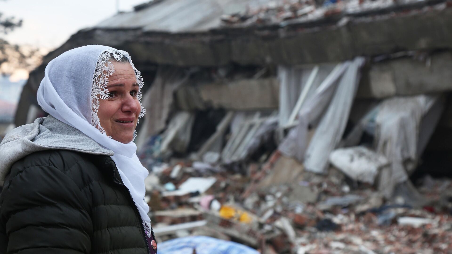 Женщина наблюдает за спасательными работами на месте разрушенного в результате землетрясения здания в турецком городе Диярбакыр - РИА Новости, 1920, 10.02.2023