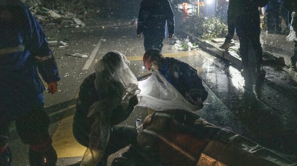 Спасатели помогают раненому рядом с завалами в Хатае, Турция