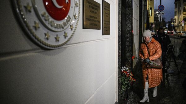 Женщина несет цветы к посольству Турции в память о погибших в результате землетрясения, которое произошло 6 февраля в турецкой провинции Кахраманмараш