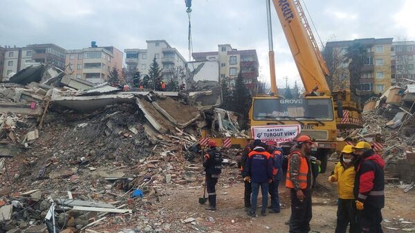 Спасатели у жилого дома, разрушенного в результате землетрясения в турецком городе Кахраманмараш