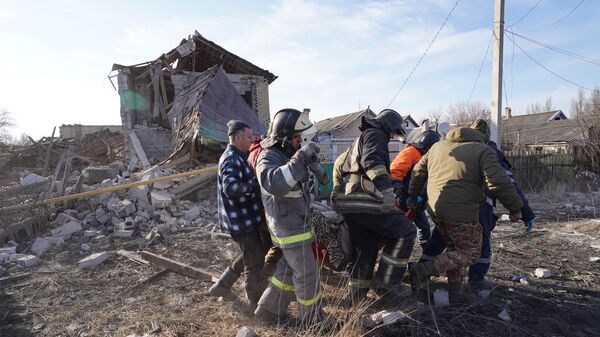 Сотрудники МЧС выносят женщину, получившую ранения в результате попадания ракеты HIMARS в жилой дом в Донецке