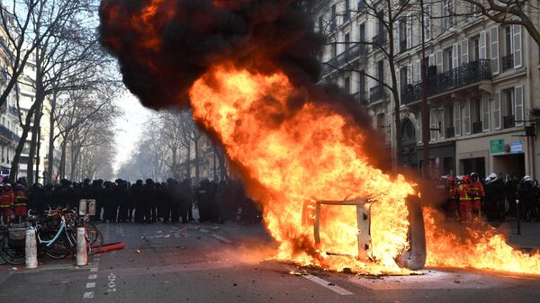 Горящий автомобиль во время акции протеста против пенсионной реформы в Париже