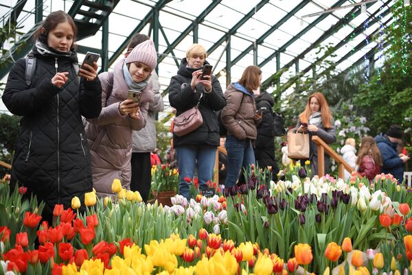 Посетительницы фотографируют цветы на крупнейшей в России зимней IX ежегодной выставке Репетиция весны в Аптекарском огороде Ботанического сада МГУ.