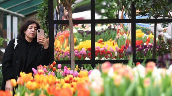 Посетительница фотографирует цветы на крупнейшей в России зимней IX ежегодной выставке Репетиция весны в Аптекарском огороде Ботанического сада МГУ