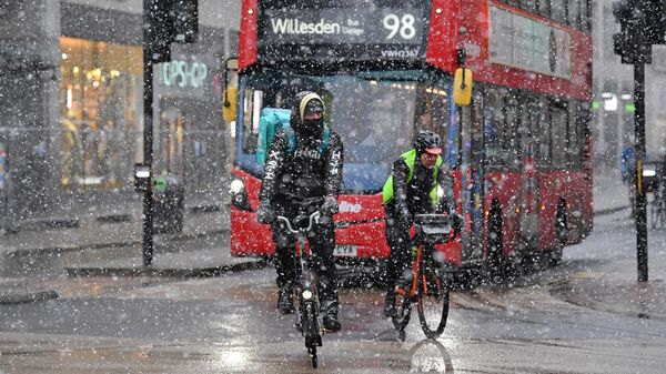 Велосипедисты на Оксфорд-стрит во время снегопада в Лондоне