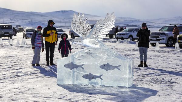 Посетители у ледяной фигуры на фестивале Айс фест на острове Ольхон в Иркутской области