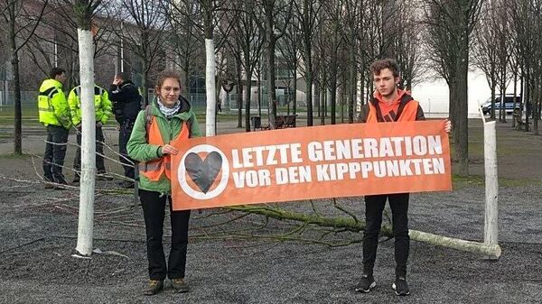 Активисты движения Последнее поколение возле спиленного дерева перед федеральным ведомством канцлера Германии Олафа Шольца
