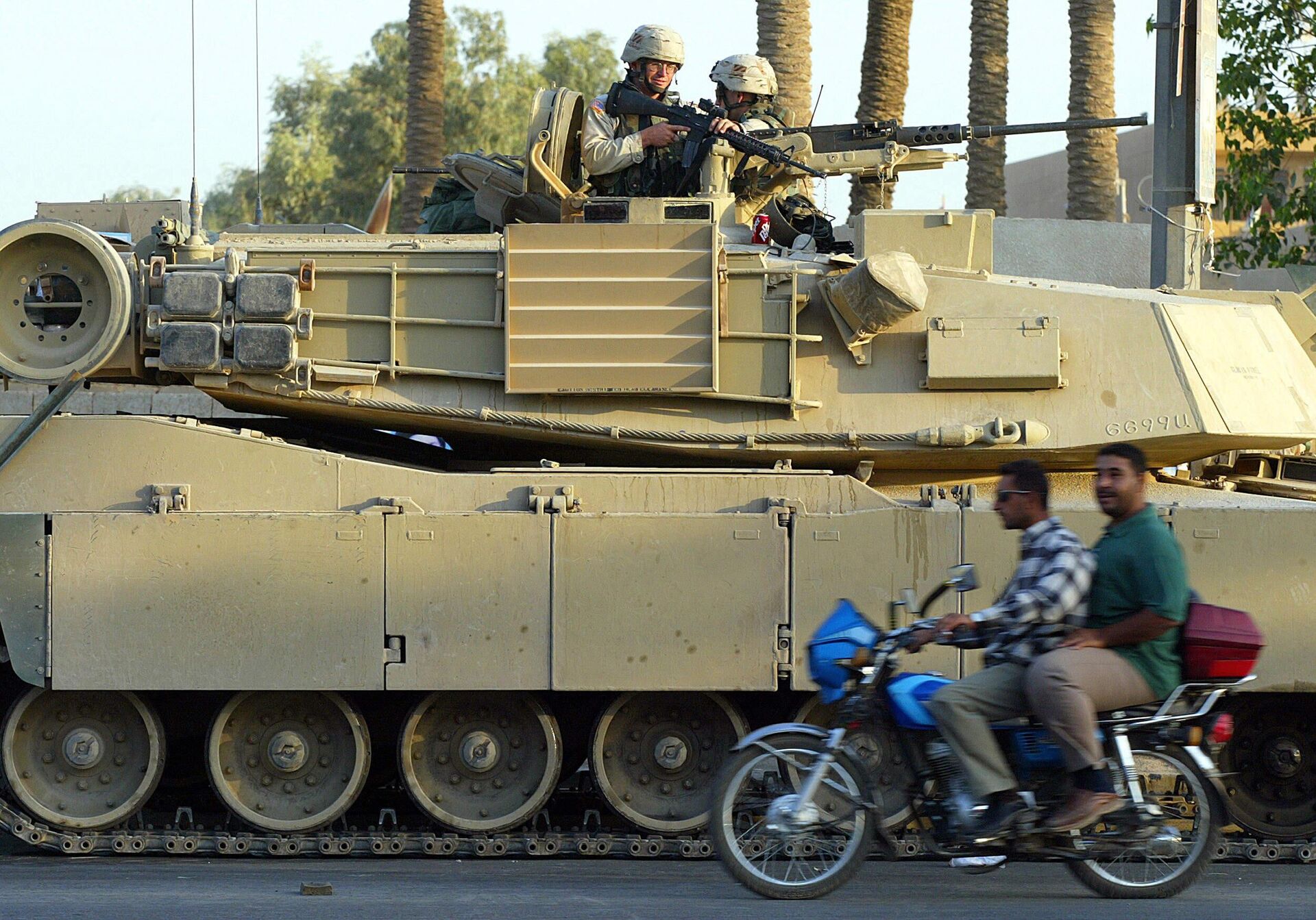 Иракцы проезжают на мотоцикле мимо американского танка M1 Abrams в Багдаде - РИА Новости, 1920, 21.02.2023