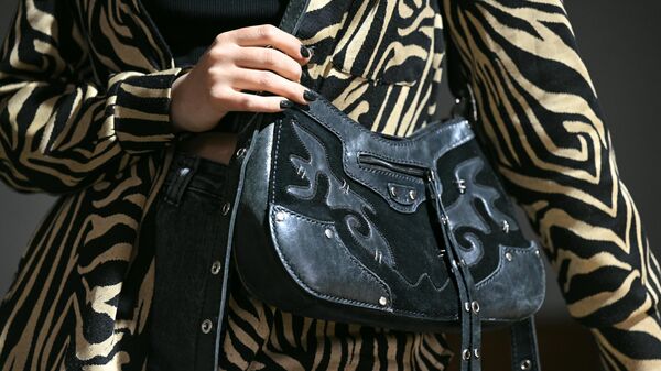 Айгель Салахова, дизайнер, демонстрирует женскую кожаную сумку ручной работы