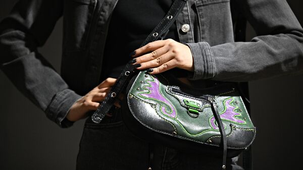 Айгель Салахова, дизайнер, демонстрирует женскую кожаную сумку ручной работы