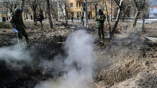 Сотрудник СЦКК ДНР у воронки от разорвавшегося снаряда РСЗО, упавшего в Ворошиловском районе Донецка после обстрела со стороны ВСУ