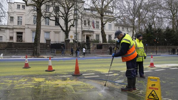 Работники коммунальной службы отмывают от краски дорогу перед посольством России в Лондоне