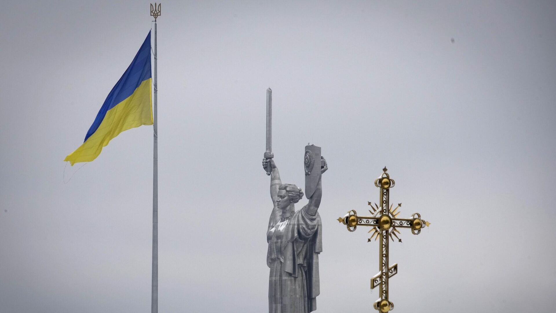 The cross of the Pechersk Lavra monastery complex against the background of the Ukrainian state flag and the Fatherland Monument in kyiv - RIA Novosti, 1920, 02/03/2023