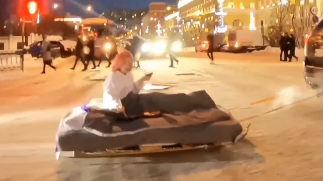 Девушка, едущая на матрасе по Мурманску