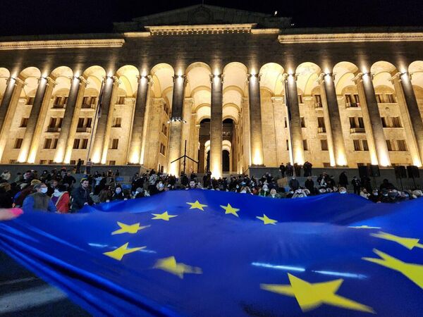 Участники акции протеста разворачивают флаг Евросоюза у здания парламента Грузии в центре Тбилиси