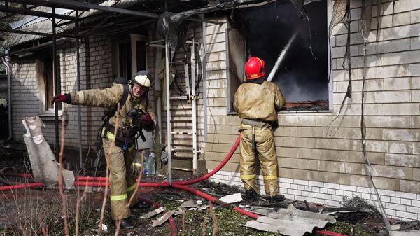 Сотрудники противопожарной службы тушат дом, сгоревший после обстрела со стороны ВСУ Киевского района Донецка