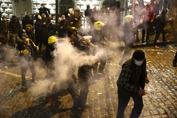 Протестующие бросают дымовую шашку в полицию у здания парламента Грузии в Тбилиси, 8 марта 2023 года