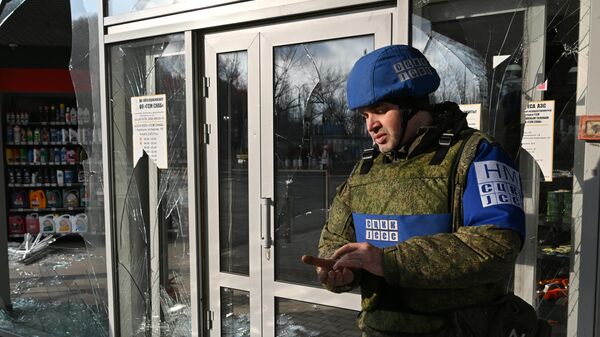 Сотрудник СЦКК у разбитых витрин магазина после обстрела со стороны ВСУ в городе Перевальске