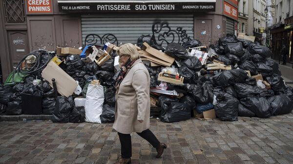 Женщина проходит мимо неубранного мусора в Париже