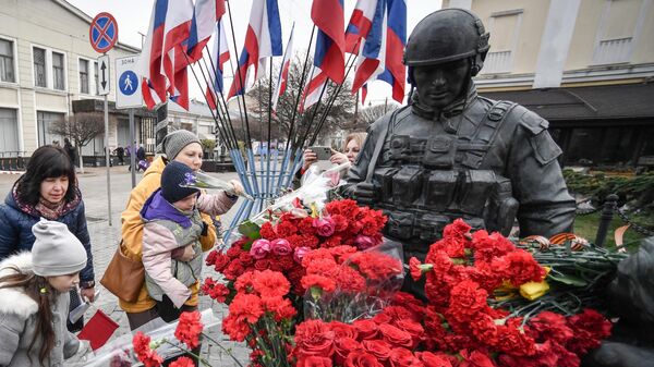 Des enfants déposent des fleurs au Monument aux gens polis à Simferopol