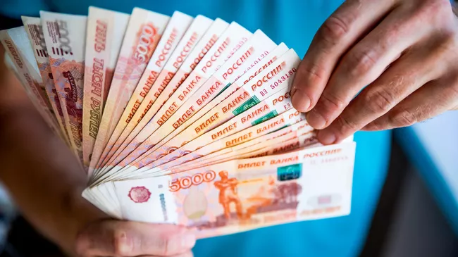Мужчина держит в руках российские рубли