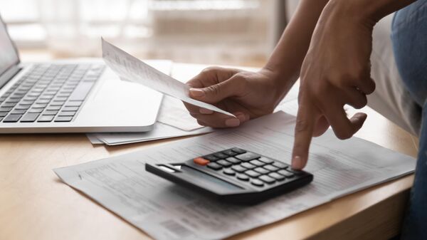 Женщина считает стоимость налога на долговой кредит на калькуляторе
