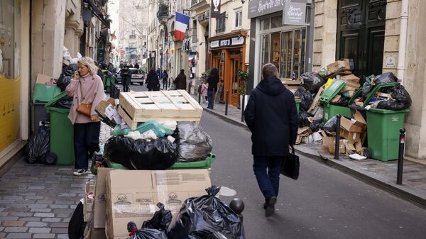 Мужчина проходит мимо неубранного мусора в Париже