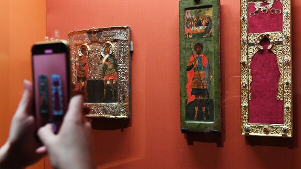 Посетительница фотографирует иконы на выставке Небесное воинство. Образ и почитание в выставочном зале Успенской звонницы Московского Кремля